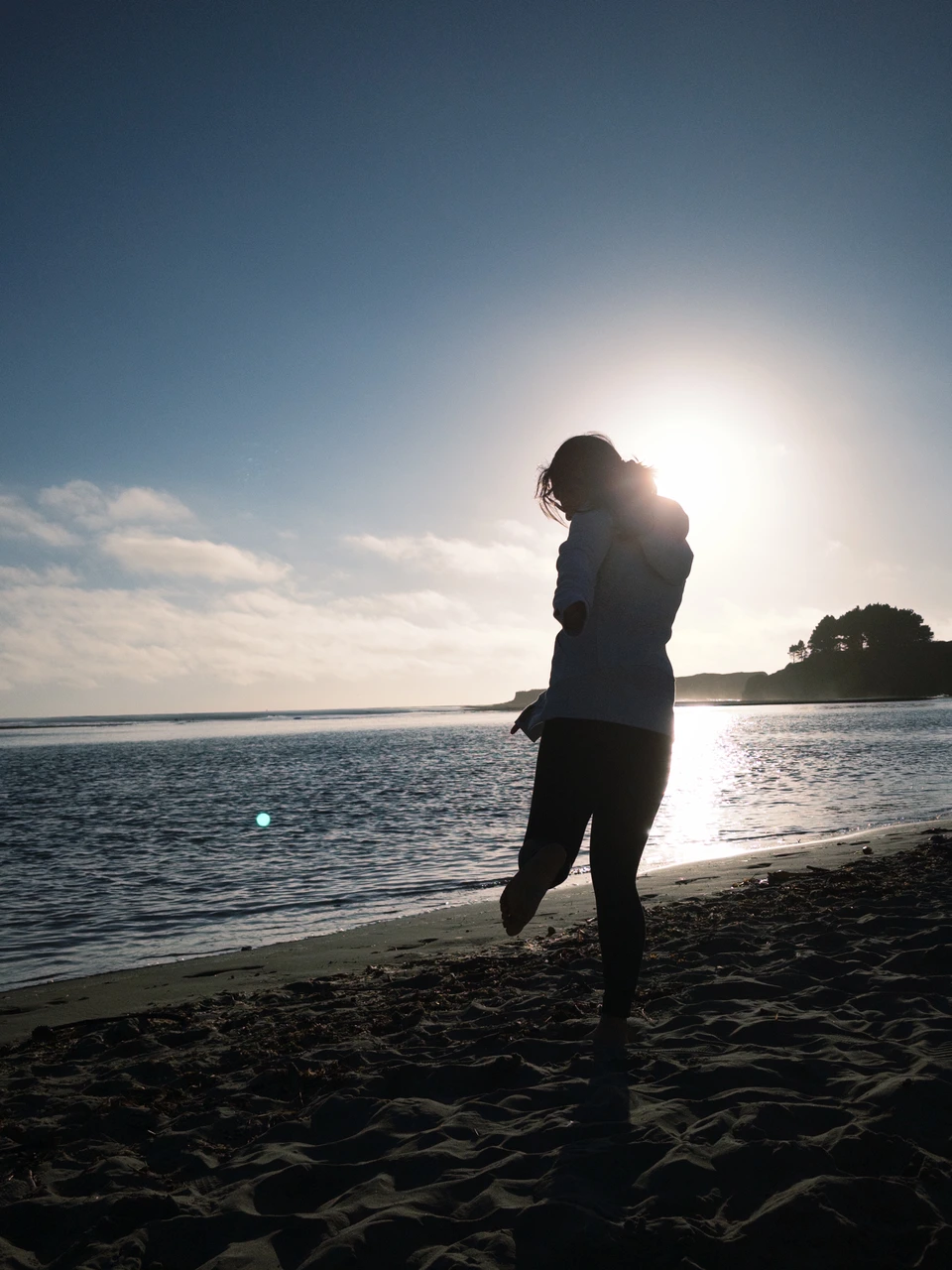 A figure walking toward the water, backlit