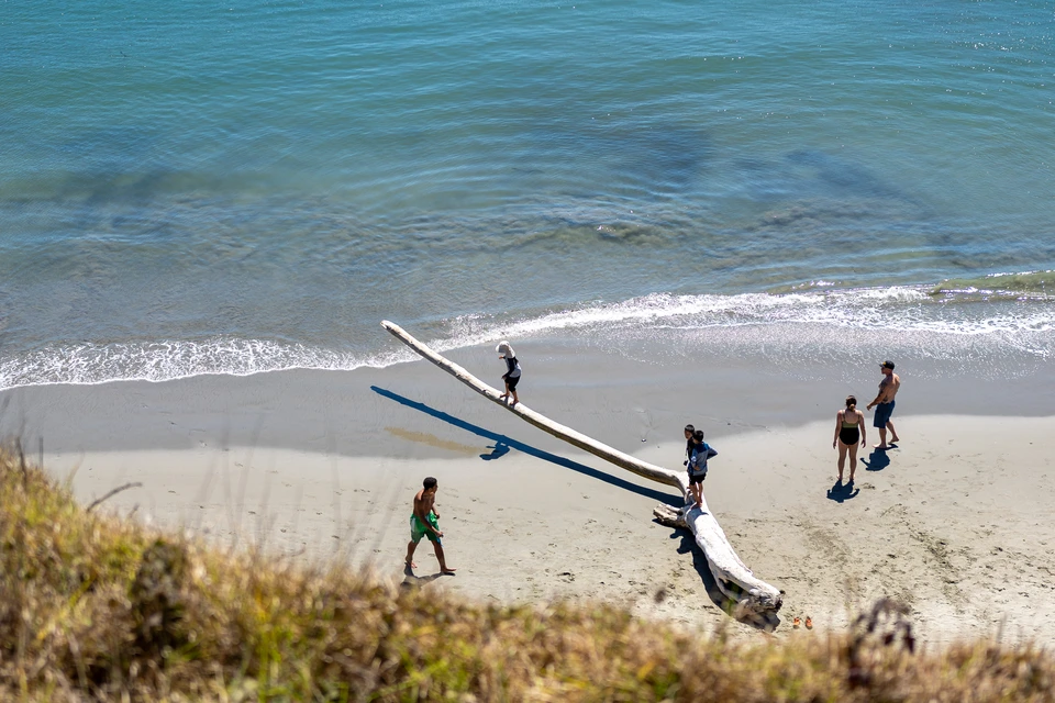 People on the beach beside a stranded pole