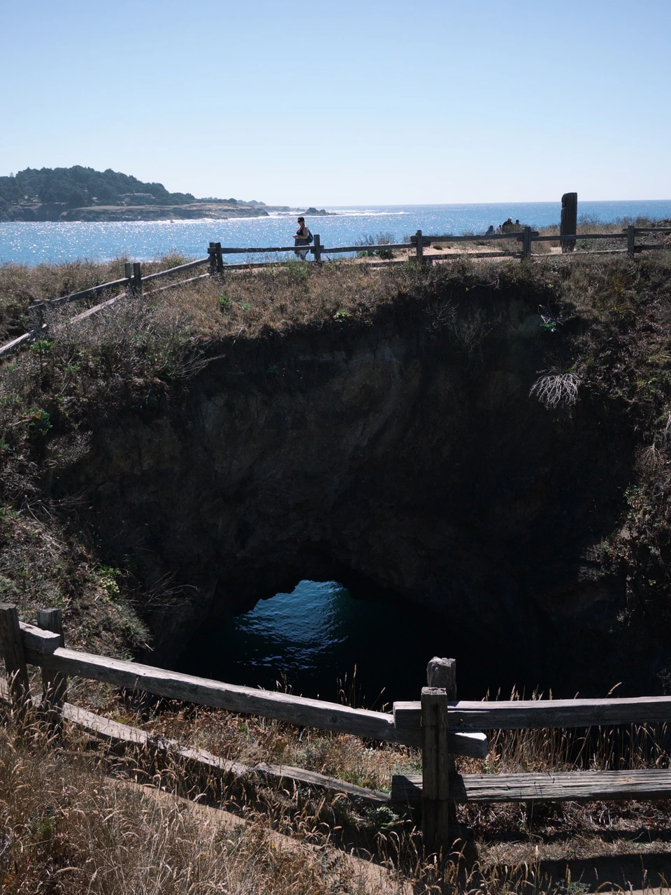 A collapsed sea cave behind a fence