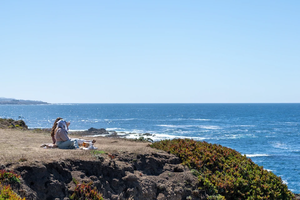 Two people sitting on the bluff, looking out