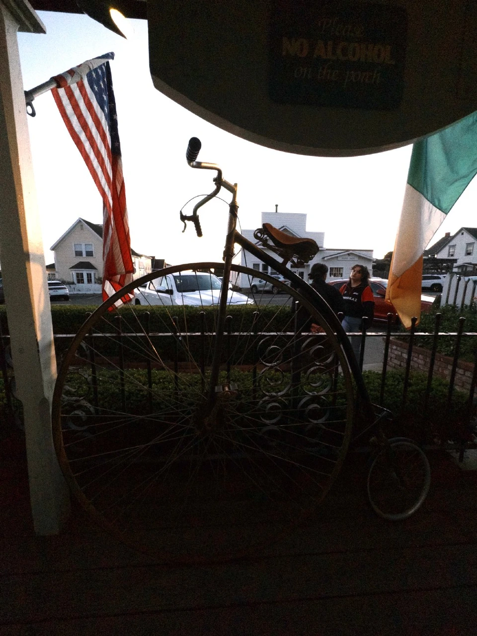An old high-wheel bicycle and a flag in a window